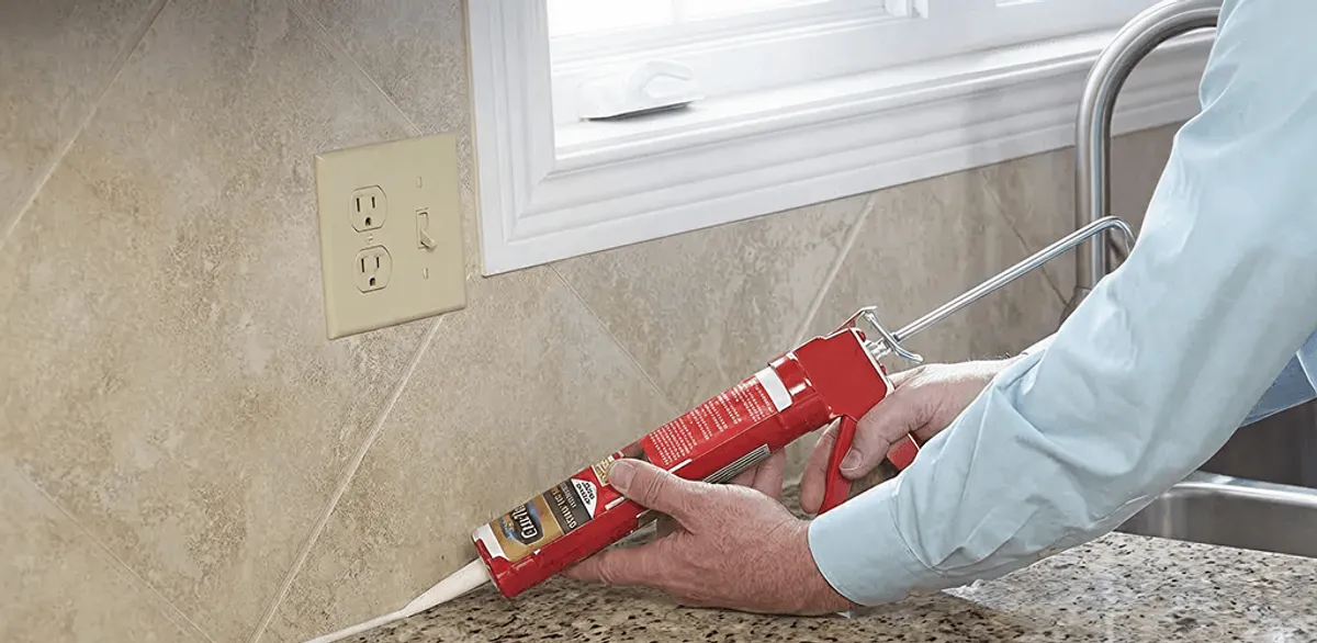Handyman applying caulk along a kitchen backsplash and countertop seam in Eugene, OR